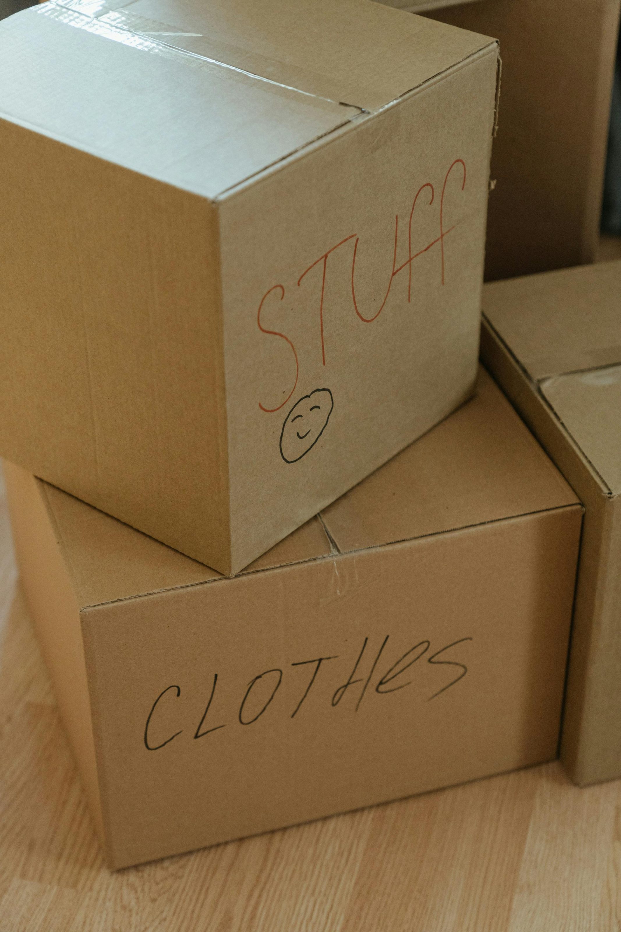 cardboard boxes stacked on top of each other being used for self storage marked 'stuff' and 'clothes'