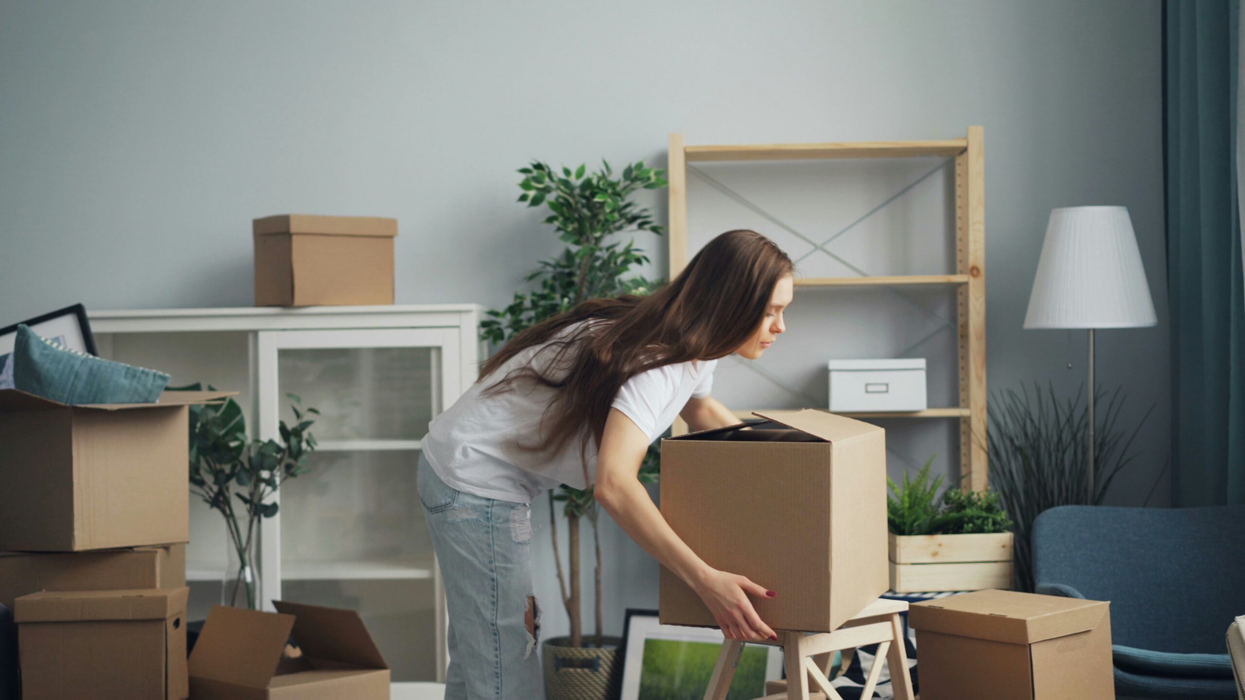 a woman bends down to lift up a storage box